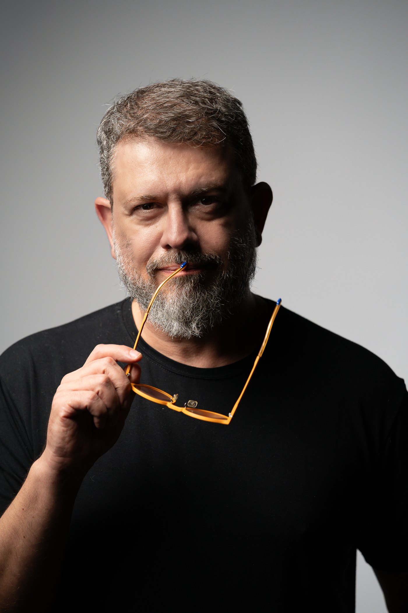 Pedro Doria, retrato, com os óculos âmbar na mão
