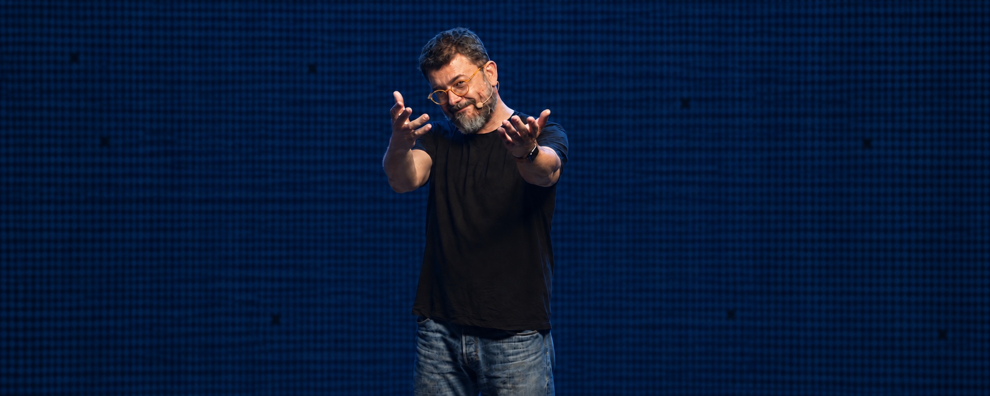 Pedro Doria no palco, de braços abertos para a plateia